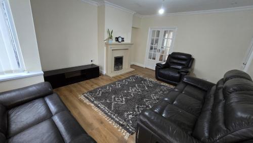 sala de estar con sofá de cuero y chimenea en Entire Three Bedroom House in Birmingham en Birmingham