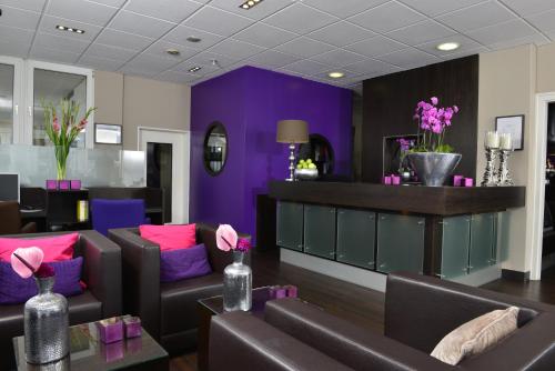 einen Salon mit lila Wänden, braunen Stühlen und Blumen in der Unterkunft Hotel Friends Hückelhoven in Hückelhoven