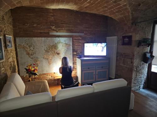 a woman sitting in a living room watching a tv at Bella Toscana in Pomarance