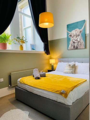 a bedroom with a large bed with a yellow blanket at The Old Schoolhouse, Kinross in Kinross