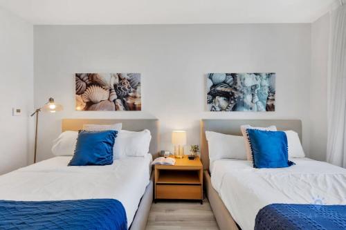 two beds in a small room with blue pillows at Spectacular View with Balcony, Pool, Near Beach in Hallandale Beach