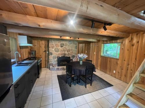 a kitchen with a table and a stone fireplace at John Wayne Cedar Oasis in Cookstown
