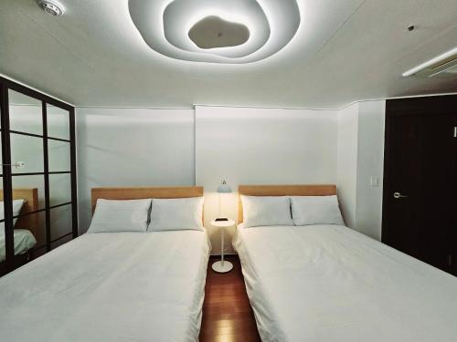 two beds in a small room with a ceiling at Ciel de Mer in Busan