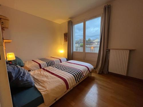 une chambre avec deux lits et une grande fenêtre dans l'établissement Duplex élégance, à Arcueil