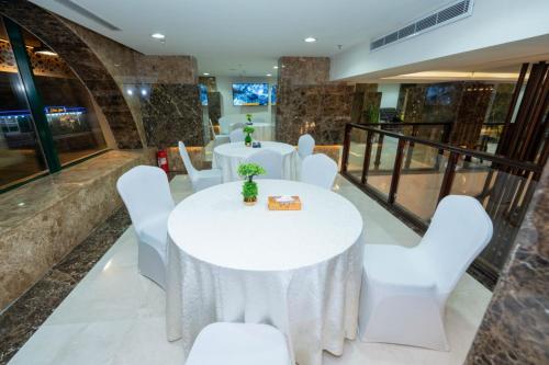 un salón de banquetes con mesas blancas y sillas blancas en Rizq Palace Hotel, en La Meca