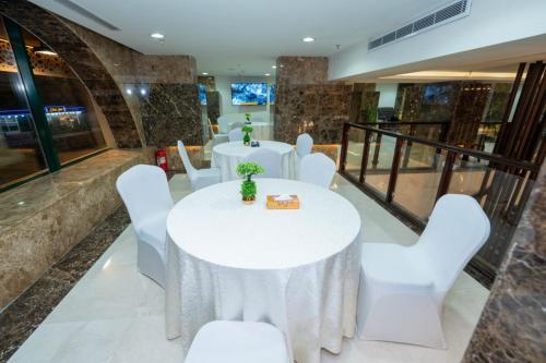 a banquet hall with white tables and white chairs at Rizq Palace Hotel فندق قصر رزق in Makkah