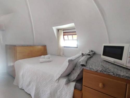 um quarto branco com uma cama e uma televisão em Cabana Lagoeiro Tucuns em Búzios