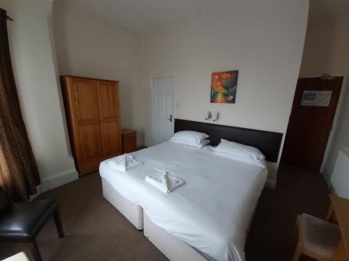 um quarto com uma grande cama branca com lençóis brancos em Channel View Hotel em Sandown