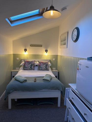 um quarto com uma cama e um relógio na parede em The Little Garden Hideaway with Stunning Sea Views and Garden em Holyhead