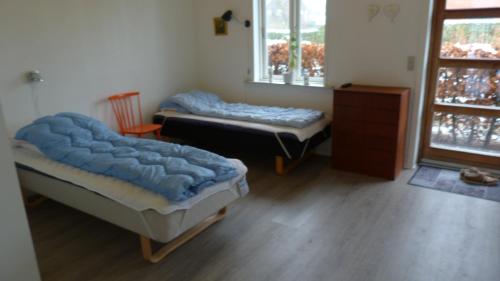 a room with two beds and a chair and a window at (id. 099) Grønnevej 35 in Esbjerg