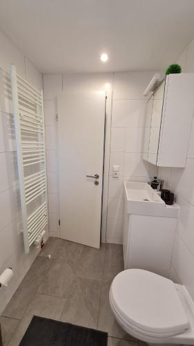 Baño blanco con aseo y lavamanos en Ferienappartement Jung, en Kamp-Lintfort