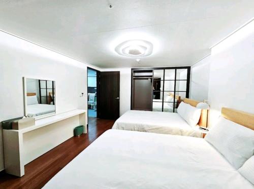a white bedroom with two beds and a mirror at Ciel de Mer in Busan