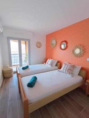 deux lits dans une chambre aux murs orange dans l'établissement La Palmeraie 2 chambres, à Sainte-Maxime
