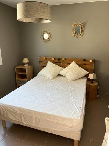 une chambre avec un grand lit avec des draps et des oreillers blancs dans l'établissement Maison avec cour située à 2 minutes des plages, à Six-Fours-les-Plages