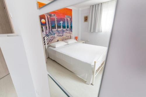 2 Bedrooms Apartment close to metro Dafni in Athens في أثينا: غرفة نوم بسرير ابيض ولوحة على الحائط
