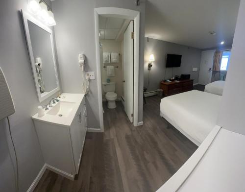 a white bathroom with a bed and a sink at Trade Winds on the Bay in Rockland