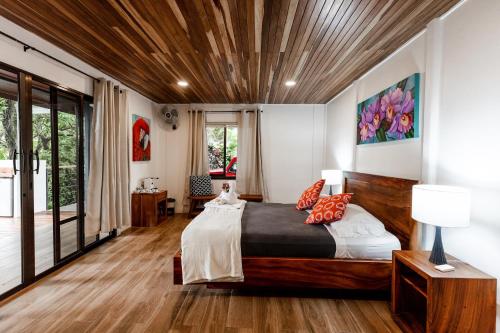 sypialnia z dużym łóżkiem i drewnianym sufitem w obiekcie Sueño Río Celeste Boutique B&B w mieście Bijagua