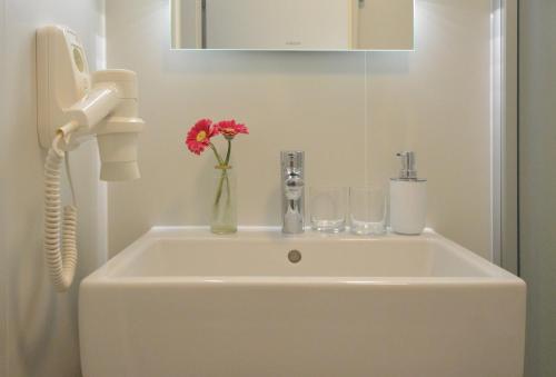 a bathroom sink with a phone and a vase with flowers at Appartement-Villa Steinfurth in Binz