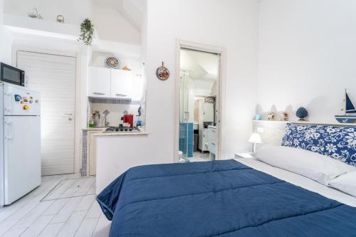 カステッランマーレ・デル・ゴルフォにあるAffittacamere Ceciliaの白いベッドルーム(青いベッド1台付)、キッチンが備わります。
