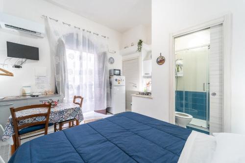 a bedroom with a blue bed and a kitchen at Affittacamere Cecilia in Castellammare del Golfo