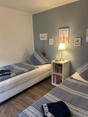 a room with two beds and a lamp and a book shelf at Strandkojen in Trassenheide