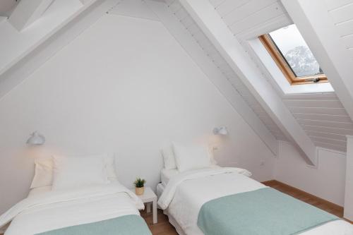 two beds in a white room with a window at Ático Camino Real by BeValle in Panticosa