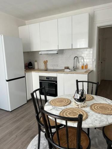 une cuisine avec une table et des chaises et une cuisine avec des placards blancs dans l'établissement Le cocon Lahô - Bel appartement refait à neuf, à Saint-Denis
