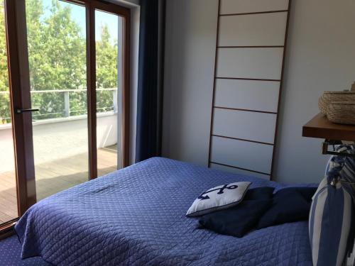 a bedroom with a blue bed and a window at Apartament Aloza 7 na wydmie w Juracie in Jurata