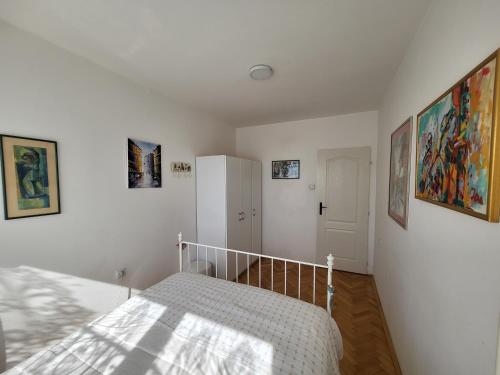 a white bedroom with a bed and a refrigerator at Happy Place in Niš