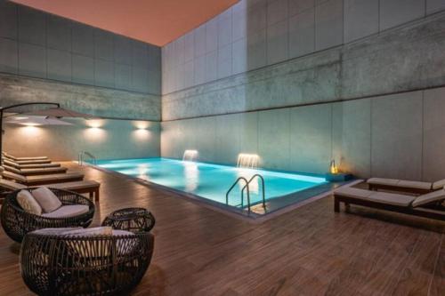 una piscina en una habitación con sillas y mesa en Met Moderno Departamento en Lima