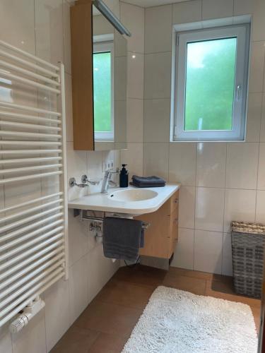 baño con lavabo, ventana y espejo en CROWN LIVING Design Apartment - 2 Schlafzimmer - Küche - gratis Parkplatz - Abstellraum für Fahrräder/Ski, en Mäder