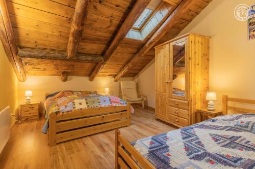 a bedroom with two beds and a wooden ceiling at Gîte Le Tsozal in Aussois