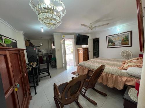 - une chambre avec un lit, des chaises et un lustre dans l'établissement Apartamentos y Estudios Manga Real, à Carthagène des Indes