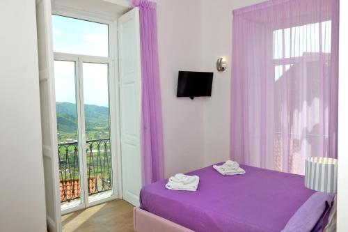 1 dormitorio con cama morada y ventana en Antares Rooms en Castellabate