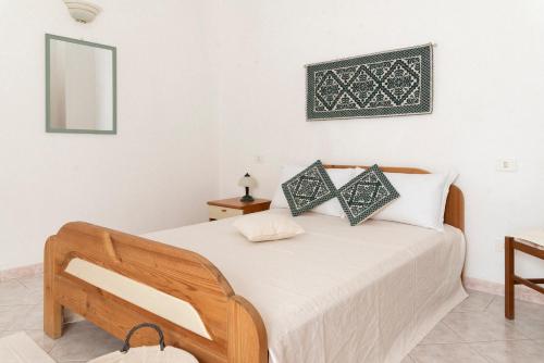 een slaapkamer met een bed met witte lakens en een spiegel bij Casa Duesse in Orosei