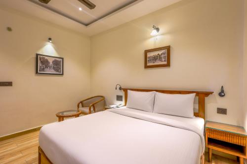 a bedroom with a white bed and a chair at Hotel Lalit Palace in Dehradun