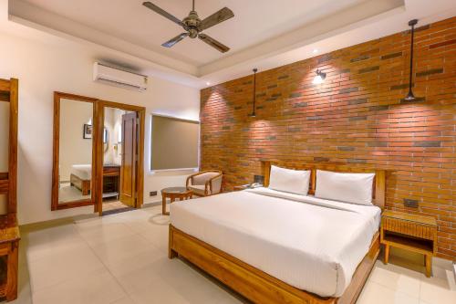a bedroom with a bed and a brick wall at Hotel Lalit Palace in Dehradun