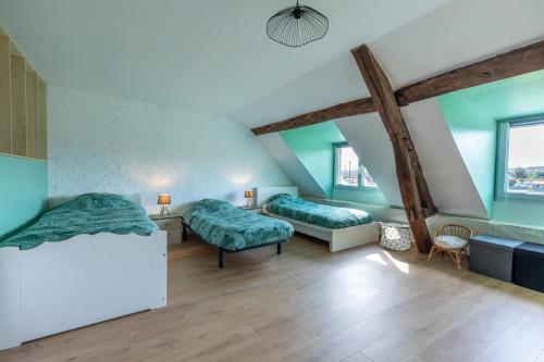 2 letti in una camera con pareti verdi e pavimenti in legno di La Villa Romaine, Jacuzzi 15 min du Zoo de Beauval a Thésée