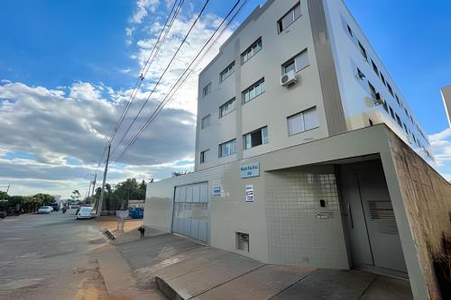 a large white building with a door in a parking lot at 207- APARTAMENTO de 2 QUARTOS no ALTO CAIÇARAS in Patos de Minas