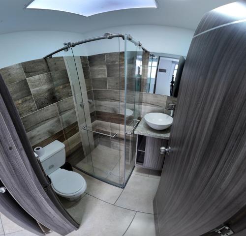 a bathroom with a shower and a toilet and a sink at Hotel Plaza Paris in Calarcá