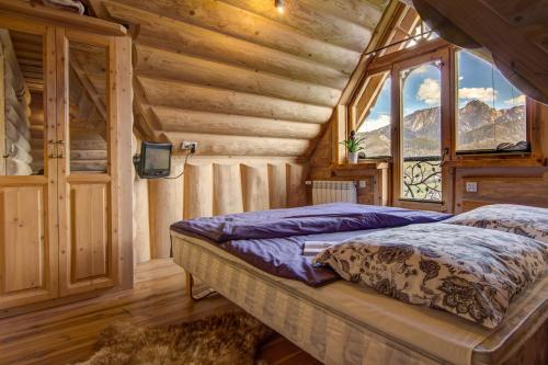 a bedroom with a bed in a log cabin at Domki Tatra Lux Zakopane in Kościelisko