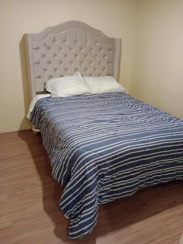 ein großes Bett mit einer blau-weißen gestreiften Decke in der Unterkunft RIMAC - EDMA SAC in Lima