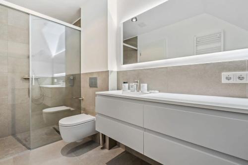 a white bathroom with a toilet and a shower at New High-End 2 BR Penthouse w Balcony in Luxembourg