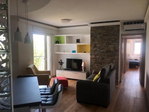 ein Wohnzimmer mit einem Sofa, Stühlen und einem TV in der Unterkunft Finestra sul mare in Monfalcone