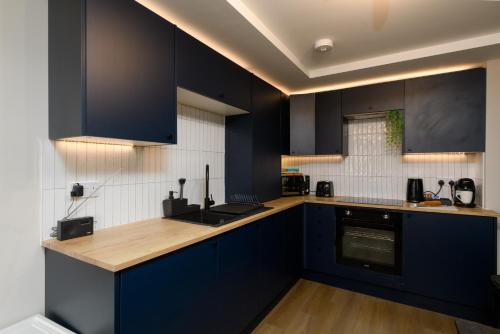 a kitchen with black cabinets and a wooden counter top at Benjamin Suite by Koya Homes - 3 Double Bedroom Apartment, Cardiff City Centre, Free Parking in Cardiff
