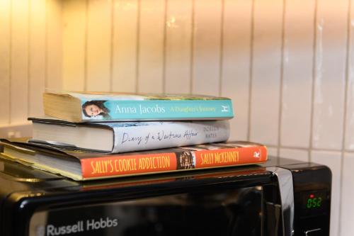 a stack of books sitting on top of a microwave at Benjamin Suite by Koya Homes - 3 Double Bedroom Apartment, Cardiff City Centre, Free Parking in Cardiff