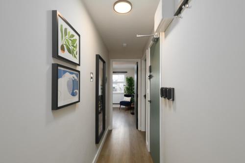 a hallway with white walls and a hallway with paintings on the walls at Benjamin Suite by Koya Homes - 3 Double Bedroom Apartment, Cardiff City Centre, Free Parking in Cardiff