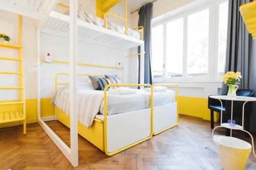 sypialnia w kolorze żółtym i białym z łóżkami piętrowymi w obiekcie Ostello Bello Lake Como w Como