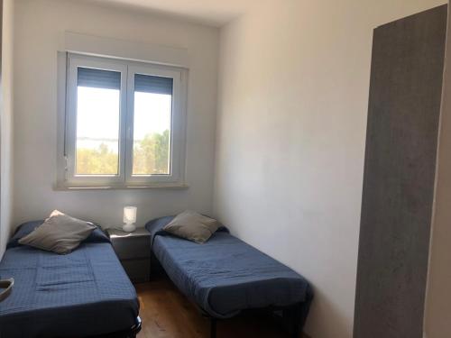 two beds in a room with a window at Finestra sul mare in Monfalcone