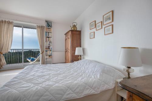 a white bedroom with a bed and a window at Sejour detente et panorama enchanteur in La Baule